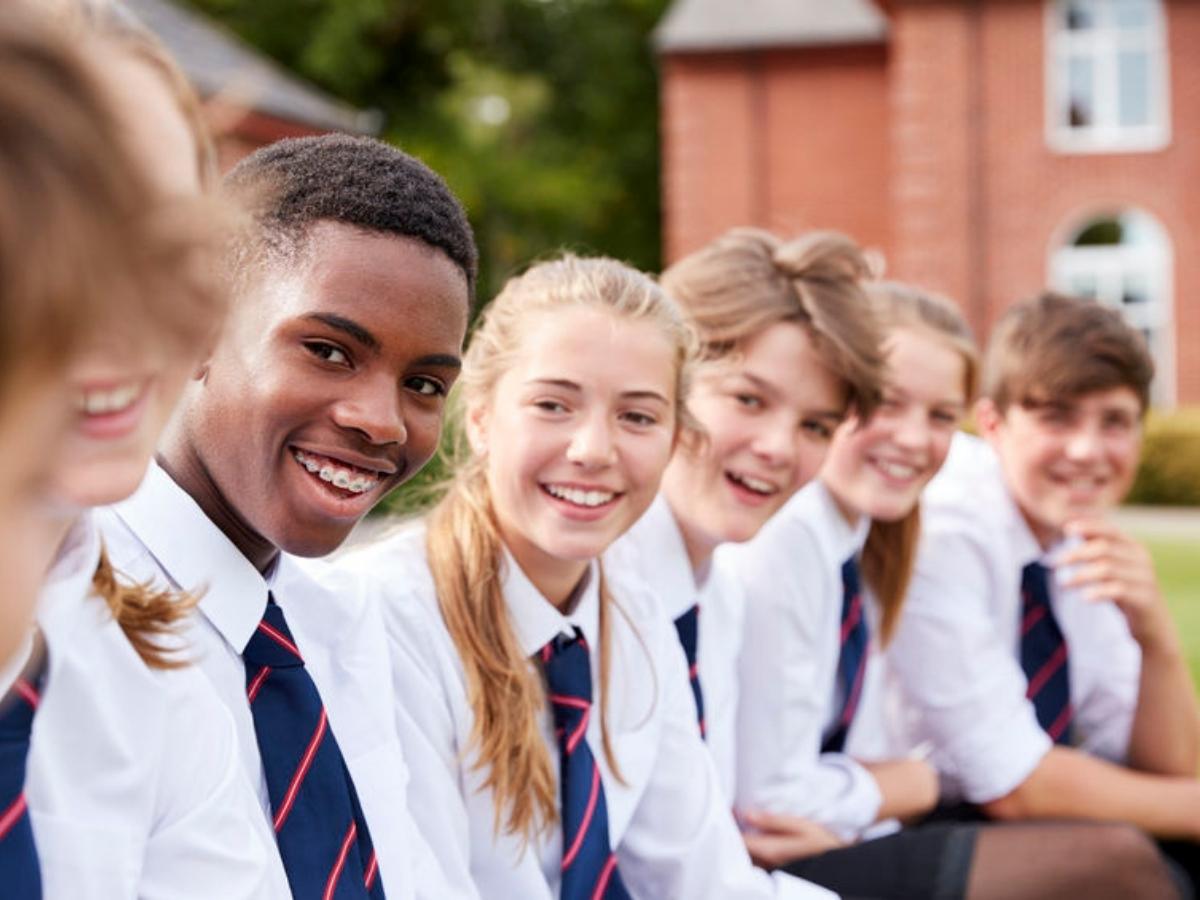 Group of teenage private school students sitting in a row outdoors for article Top Private Education in Northeast Houston for newcomers moving to Houston.