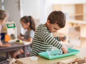 Montessori classroom with wood toys in shelves and on small rug on ground for article Montessori Schools in Houston for newcomers moving to Houston.