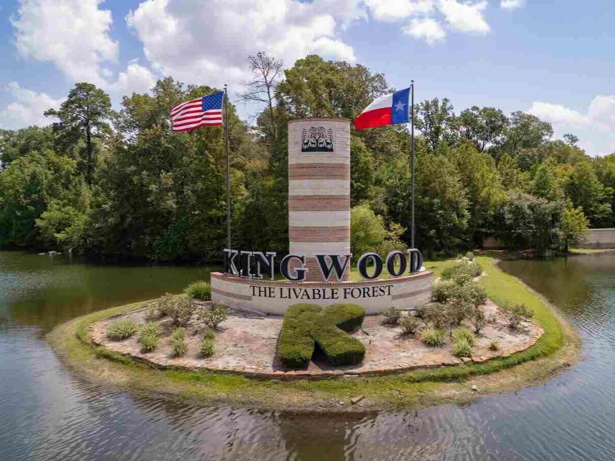 Kingwood signage "liveable forest" with flags on an island with water around it for article Kingwood Area.