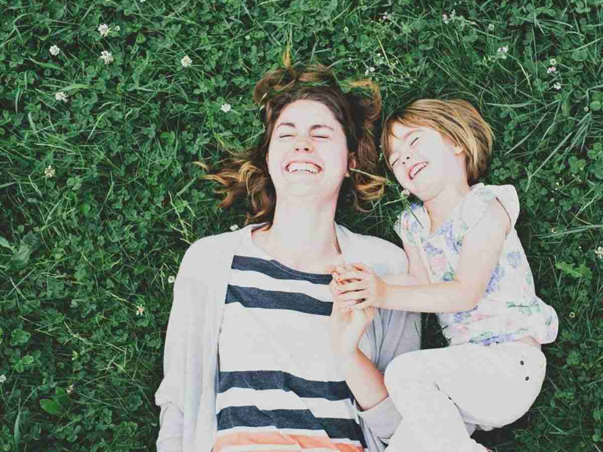 adult and child lying in the grass laughing for article Empower Behavioral Health