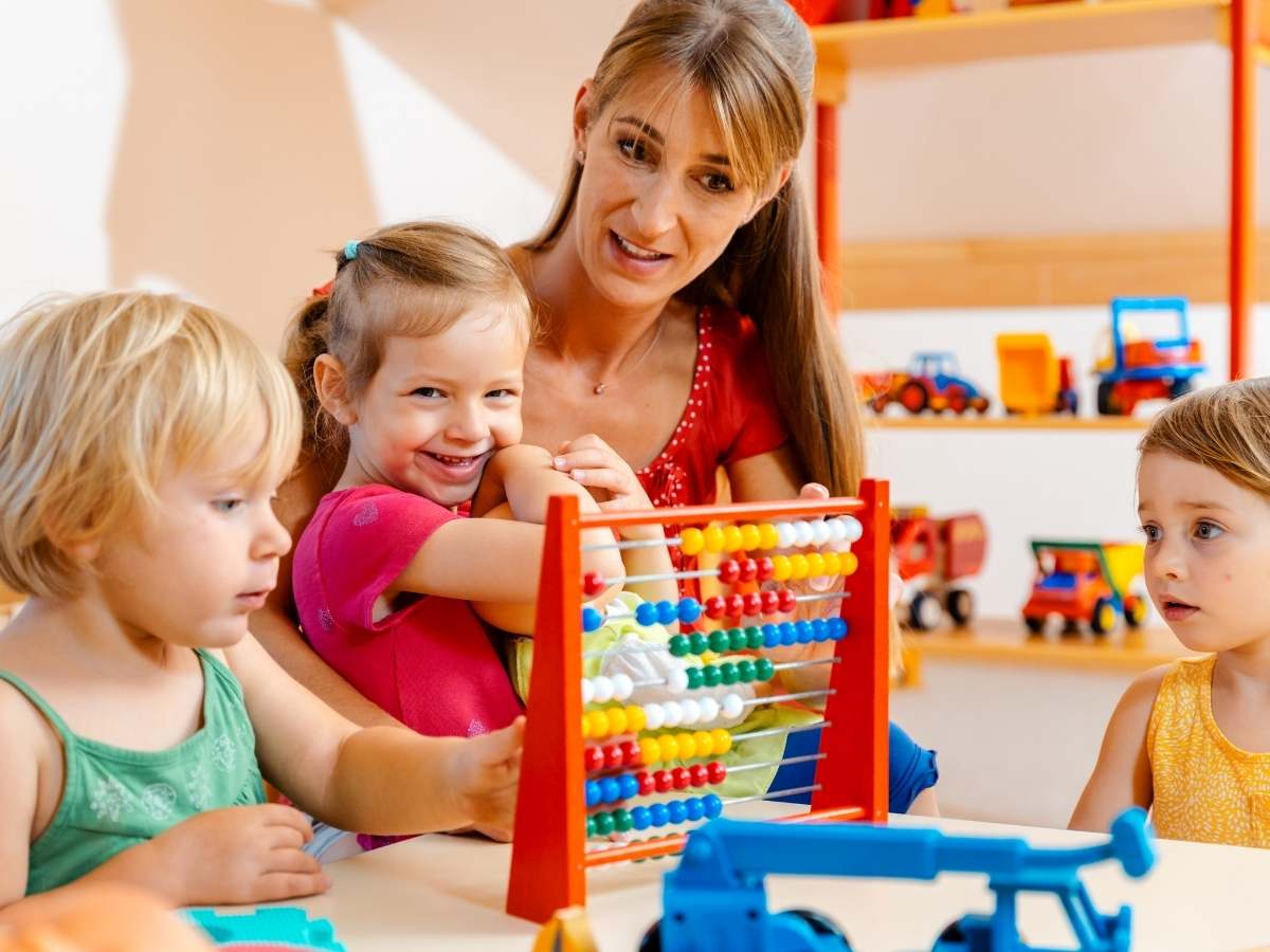 Teacher teaching preschool children who are sitting at a table learning with colorful toys for article Crossroads Early Learning Center
