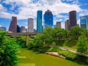 River with trees on the side and a walking and biking path on the far side and the city of downtown Houston in the background for article Why Houston Is One of the Best Cities for Recent Grads in 2025 for newcomers relocating to Houston, or recent graduates moving within Houston.