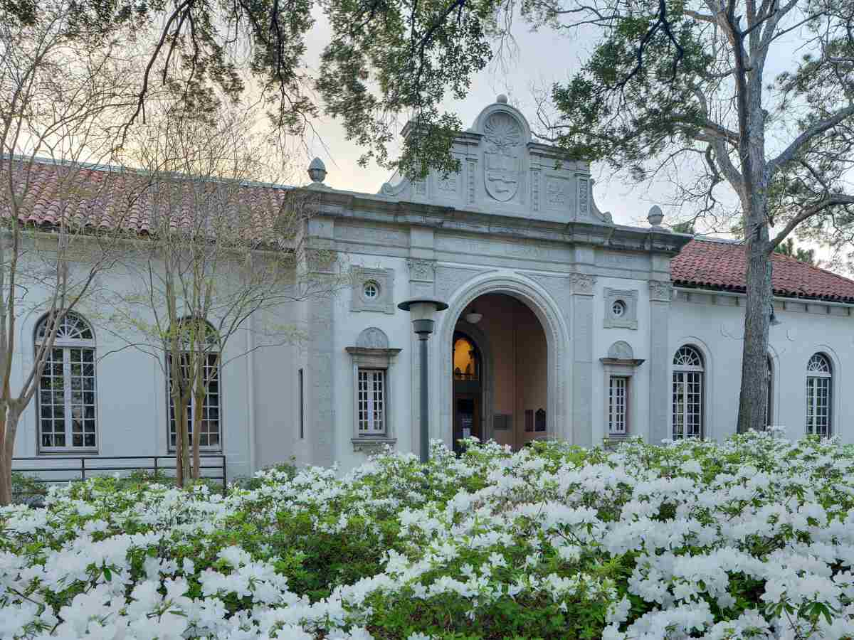 Houston Heights Public Library - Ornate building with white flowers in foreground for article Houston Heights and Greater Heights for newcomers moving to Houston.