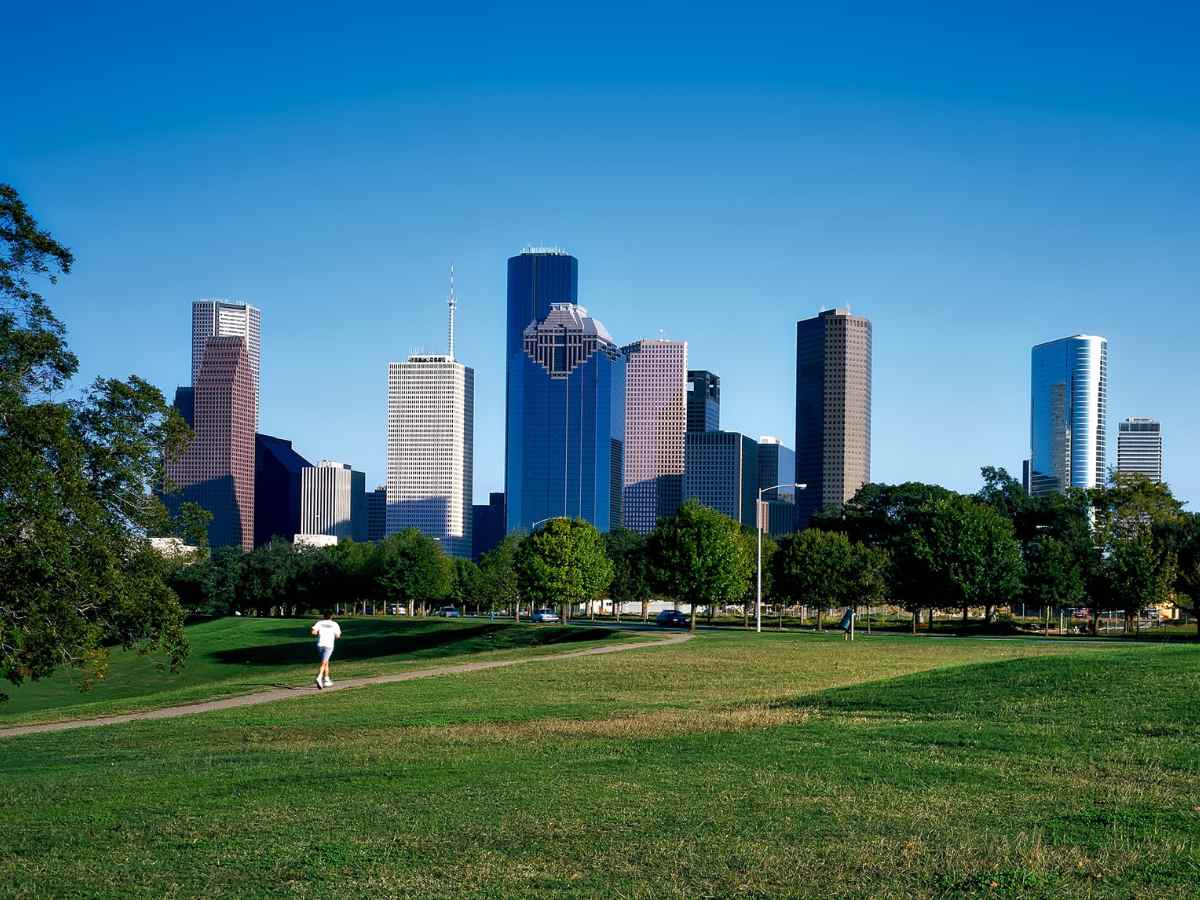 Person jogging on path with open green space and Houston skyline in background for article Tips For Moving to Central Houston for newcomers moving to Houston.