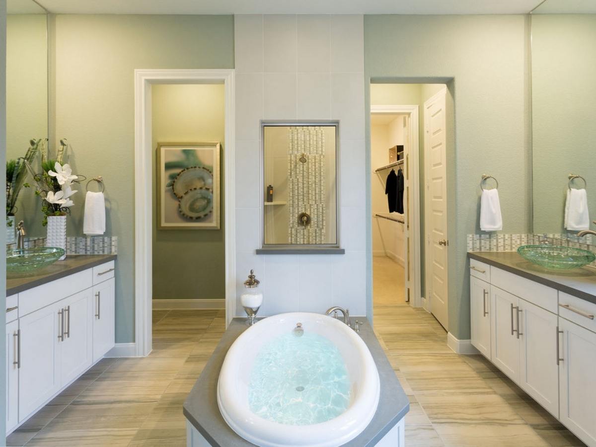 Bathroom with tub in center and vanities on each side for article Meritage Homes in Harvest Green for newcomers moving to Houston area.