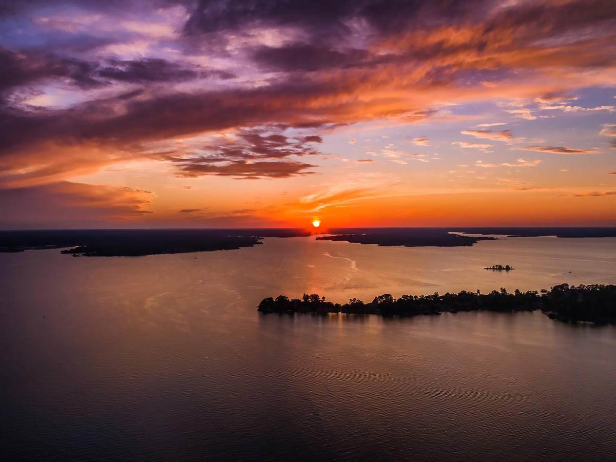 Lake Conroe at sunset with beautiful orange and purple colors in sky for article Moving to the Lake Conroe Area of Houston for newcomers moving to Houston.