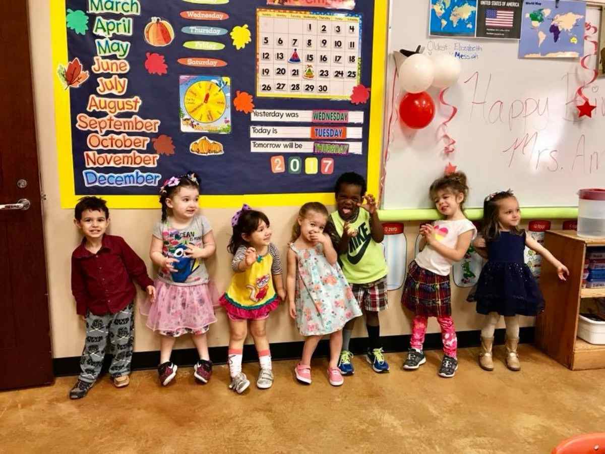 7 small students lined up for photo in front of colorful classroom wall for article Fellowship Christian Academy