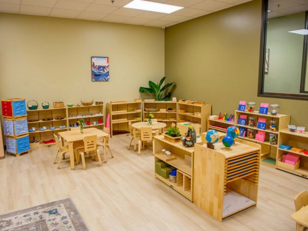 Montessori classroom with wood tables, chairs and bookshelves with all kinds of activities for kids for article Montessori Kids Universe