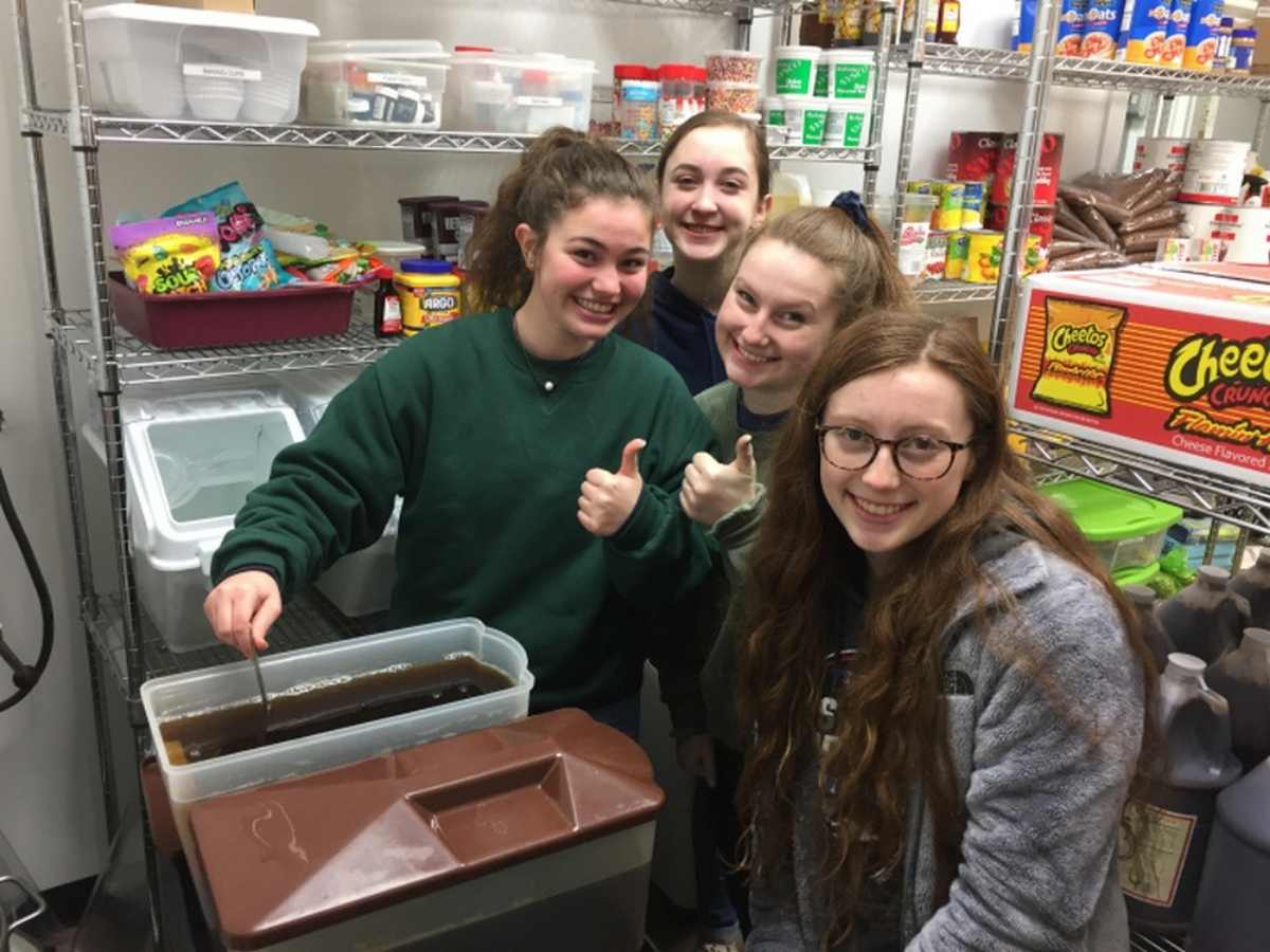4 girls posing for photo and stirring a large container of tea for article Fort Bend Christian Academy