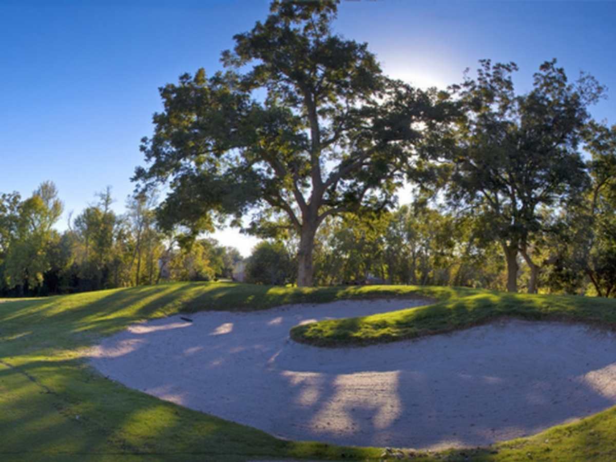 Sand trap at golf course with trees behind it for article Quail Valley Golf Course