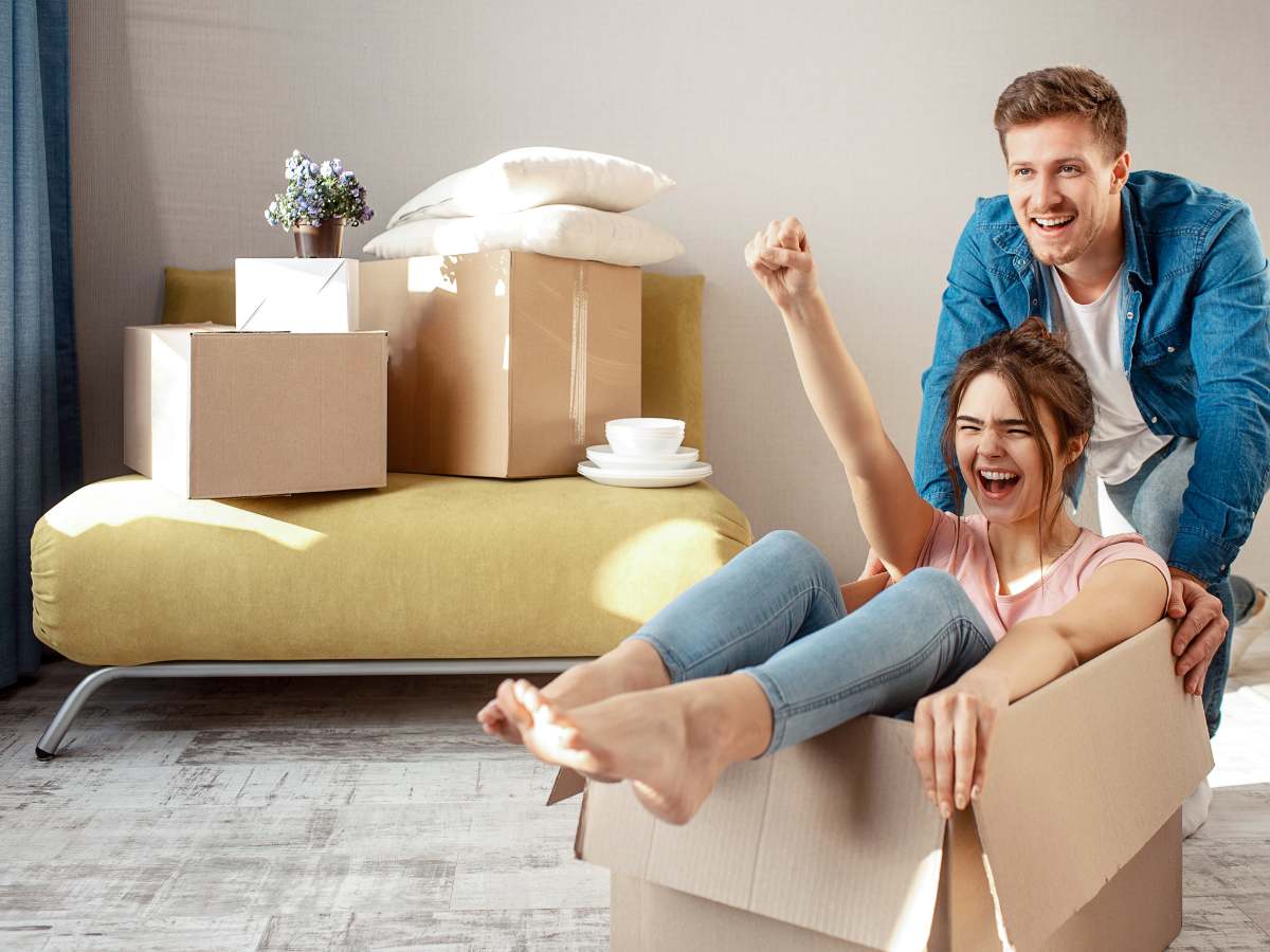 Female sitting in moving box with male pushing her from behind cheering for article Getting Settled in Houston for newcomers moving to Houston.