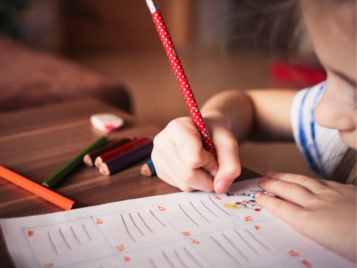 Close up of child leaning over paper using colored pencil for article 5 Popular Montgomery County School Districts for newcomers moving to Houston.