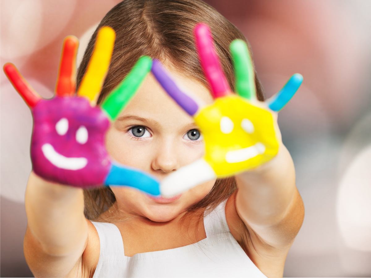 Young girl holding up hands with paint on them for article West Houston School Districts for newcomers moving to Houston.