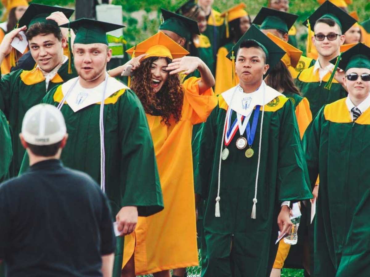 Students graduating in green and yellow caps and gowns for article Education in South Houston