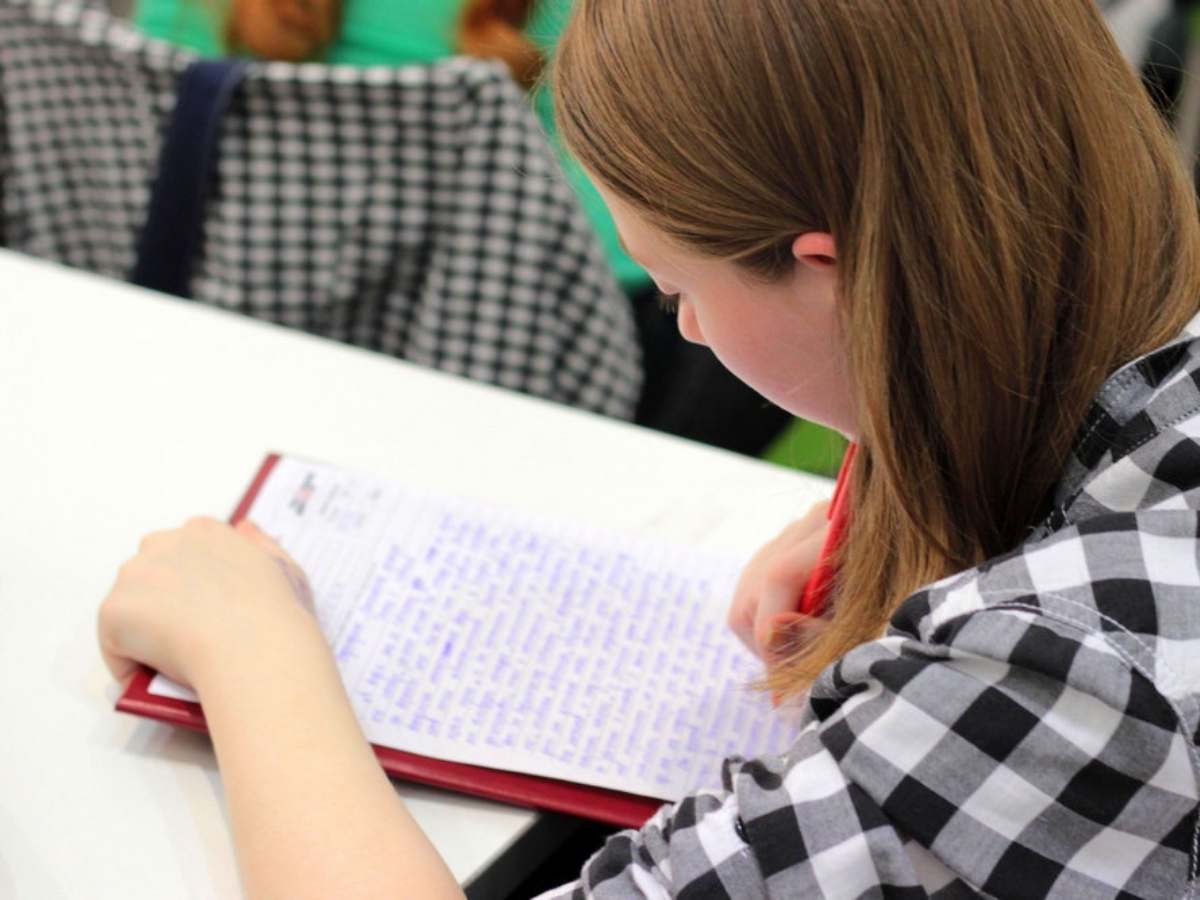Young student leaning over desk writing a report for article Clear Lake Area School Districts