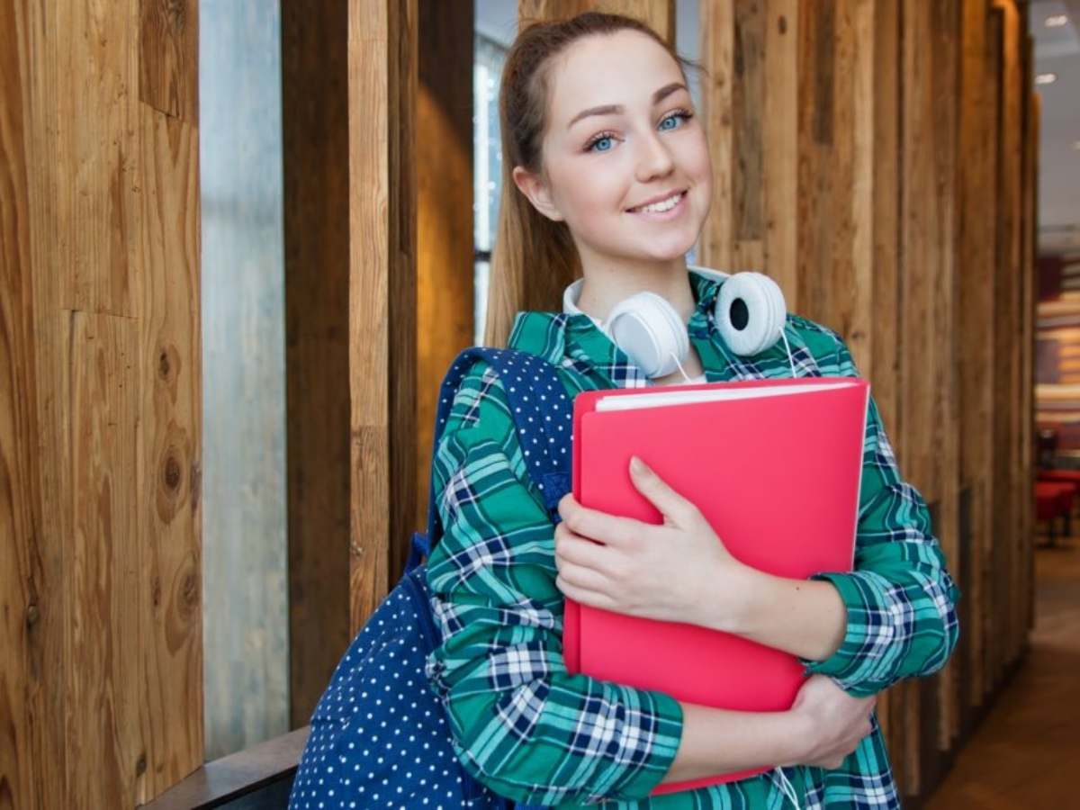 Teenager standing clutching a school notebook and wth a bag over shoulder for article Education in Central Houston