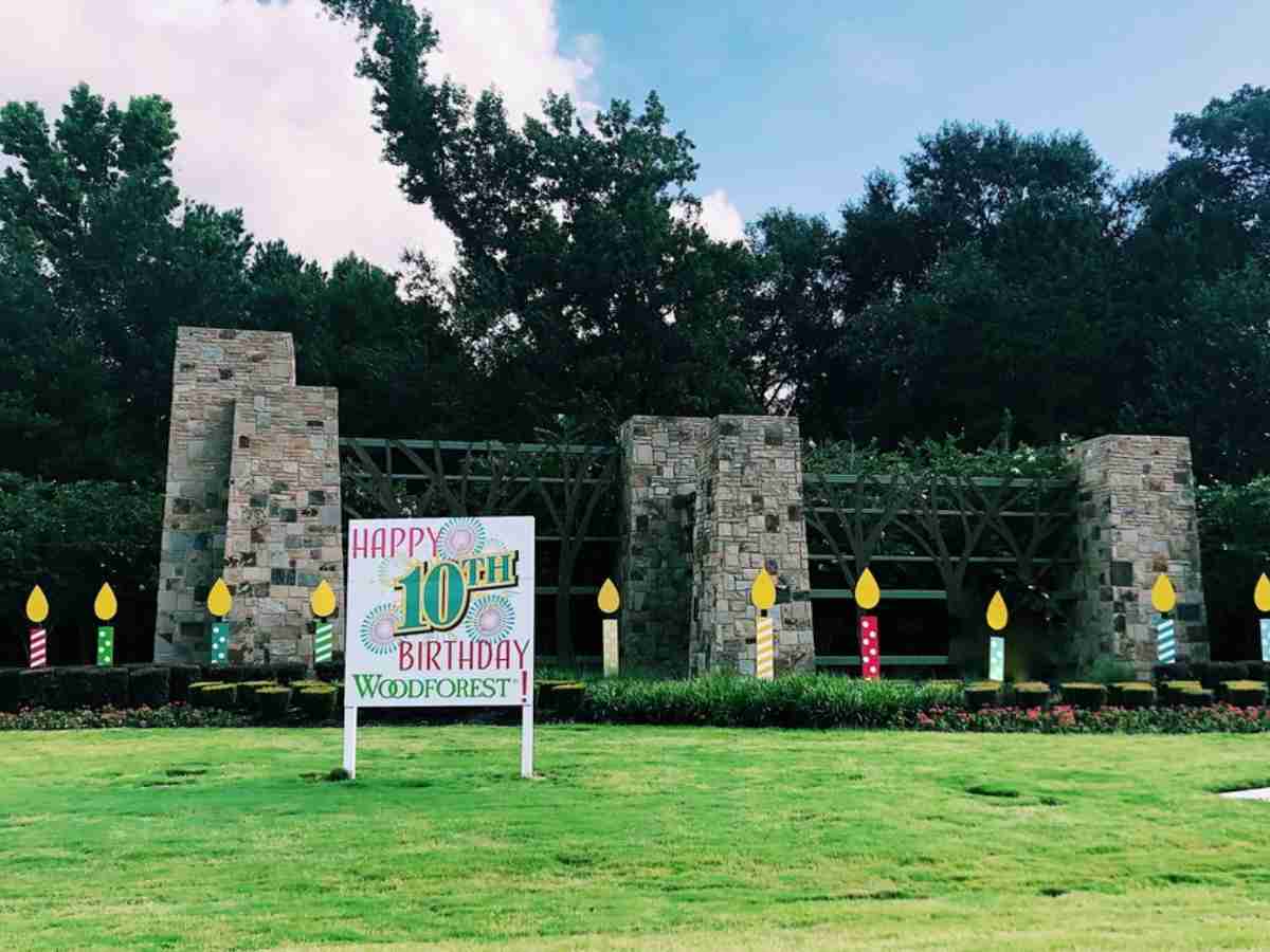 Front entrance monument for Woodforest with a happy 10th birthday sign in front and candle cutouts behind it for article Woodforest in Montgomery Texas