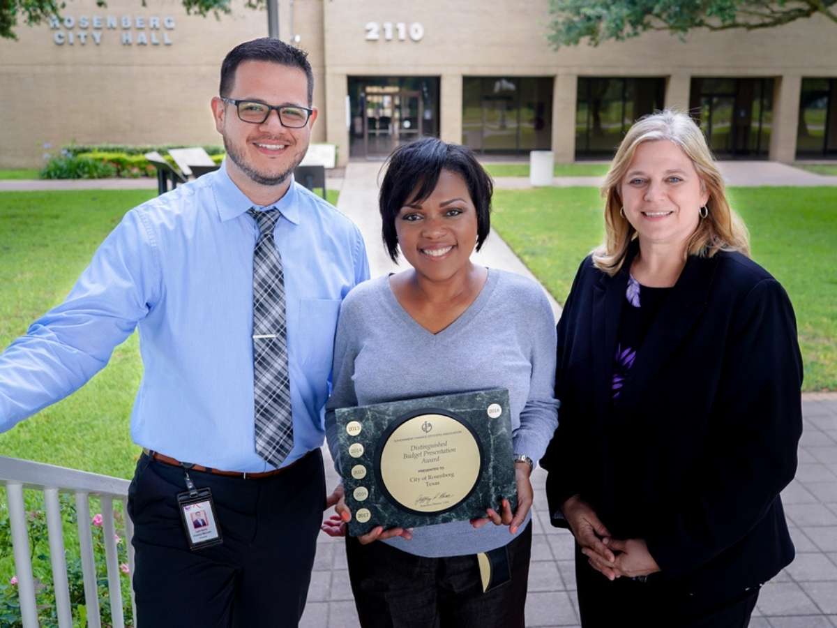 3 People posing with award for article City of Rosenberg for newcomers moving to Houston.
