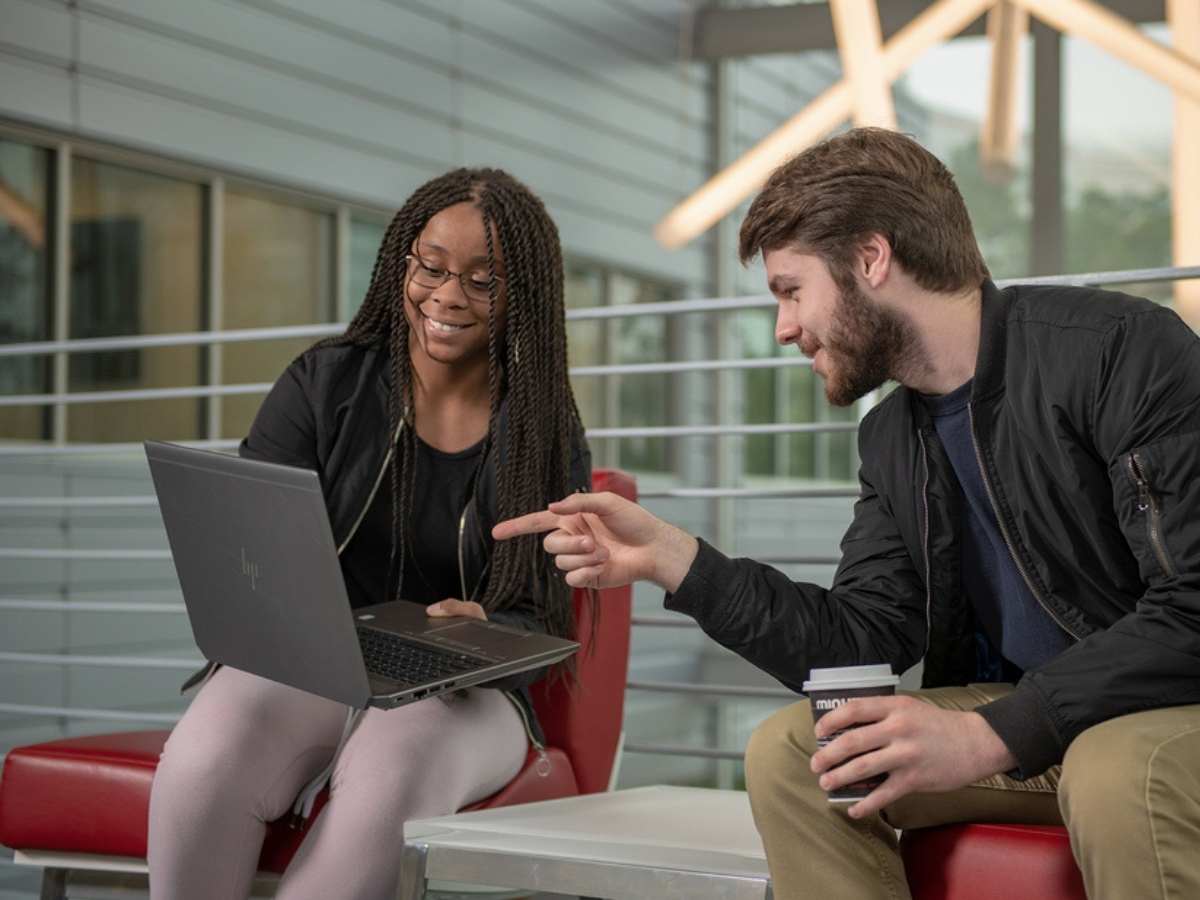 2 students sitting on chairs one holding a laptop and the other pointed at the laptop screen for article Lone Star College Ranks #1 for Online Student Enrollment in Texas