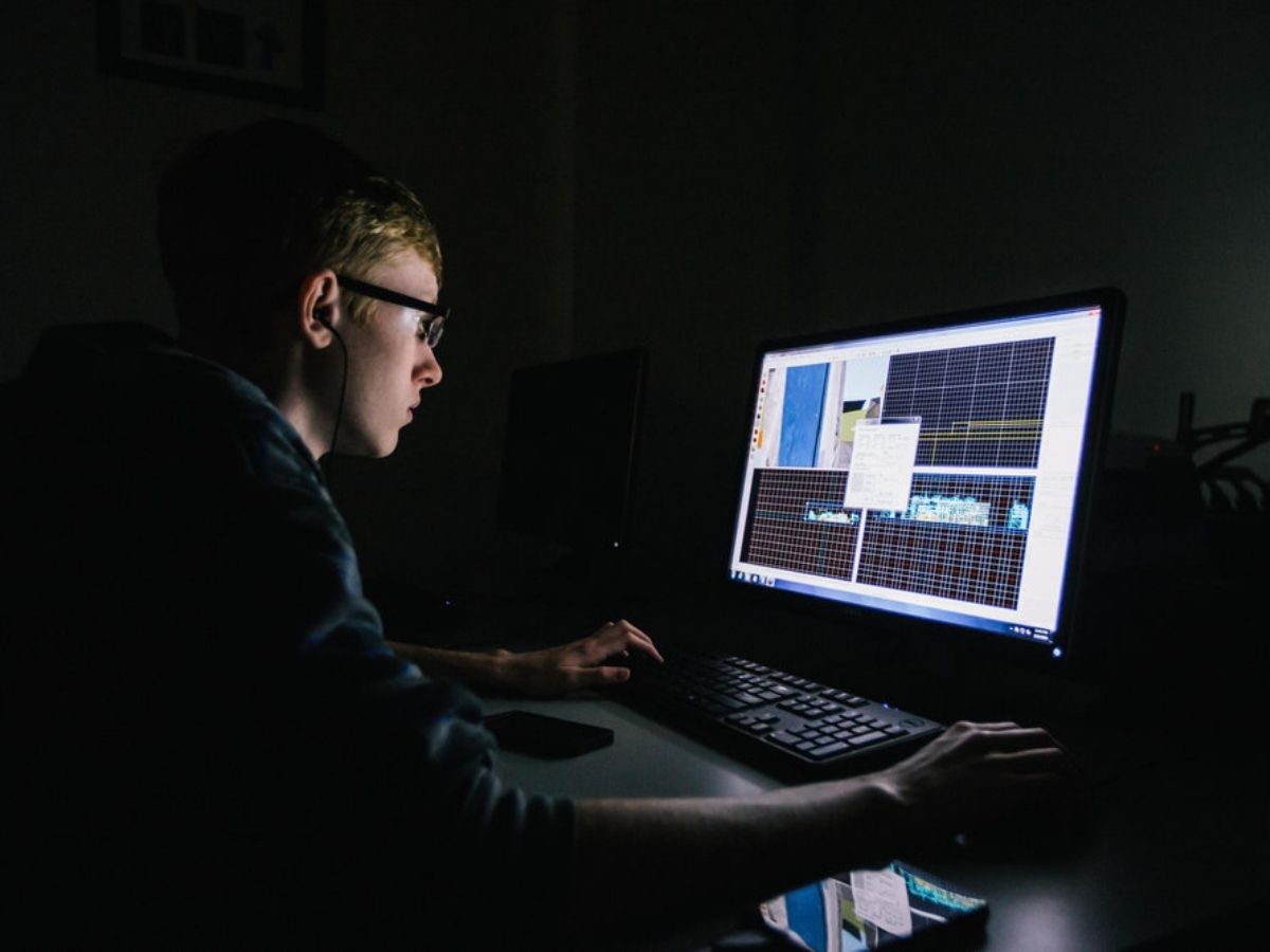 Male student on a computer in the dark with just the glow of the screen for article Houston Community College Industry Defined Programs