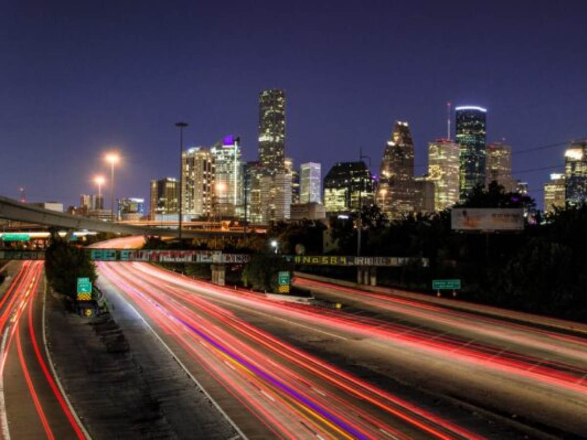 Time-lapsed photo of Houston skyline at night with light streaks as cars drive on highway for article Houston Inner Loop Living for newcomers moving to Houton.