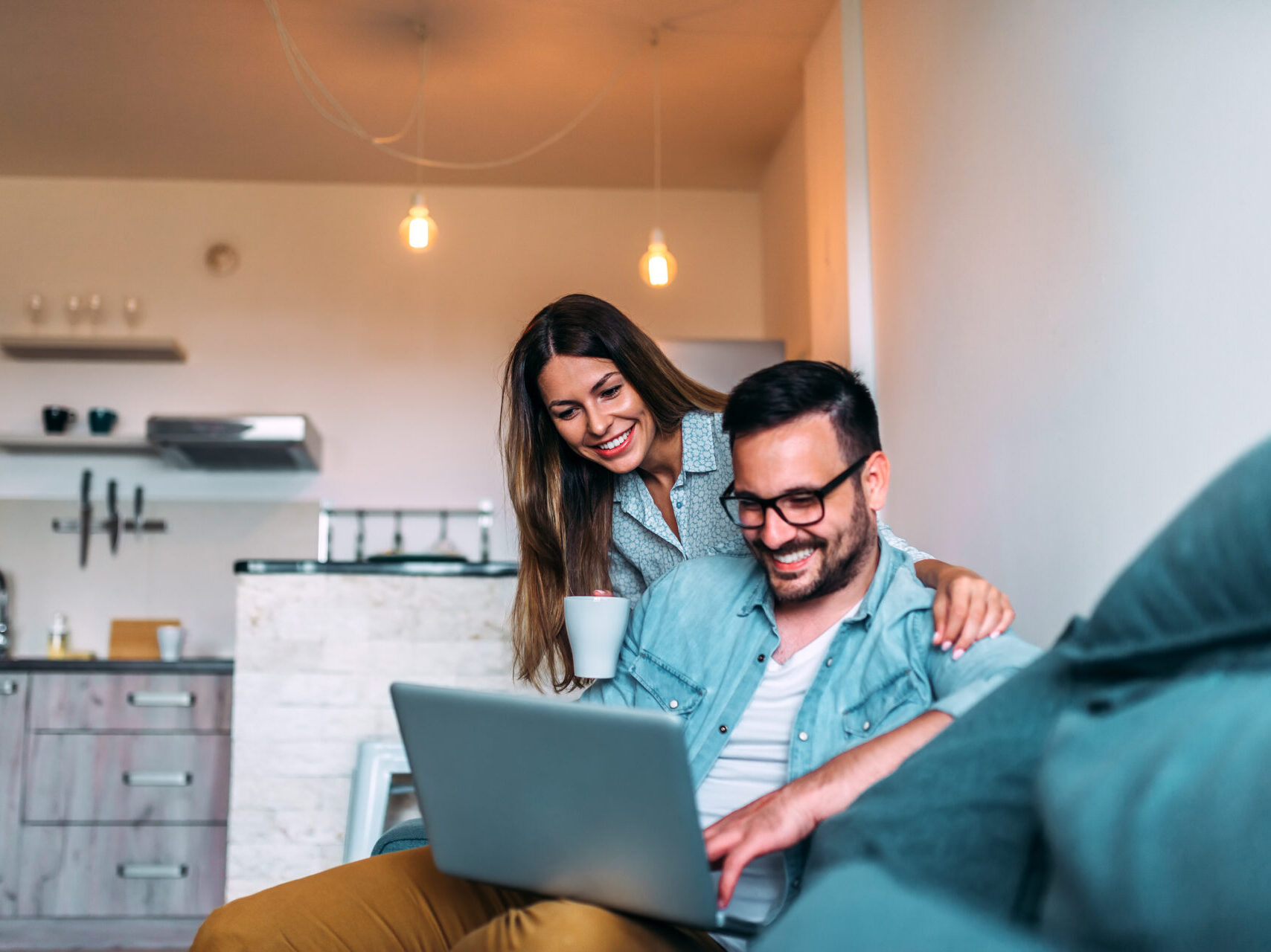 Young couple using a laptop while sitting on the sofa at home.