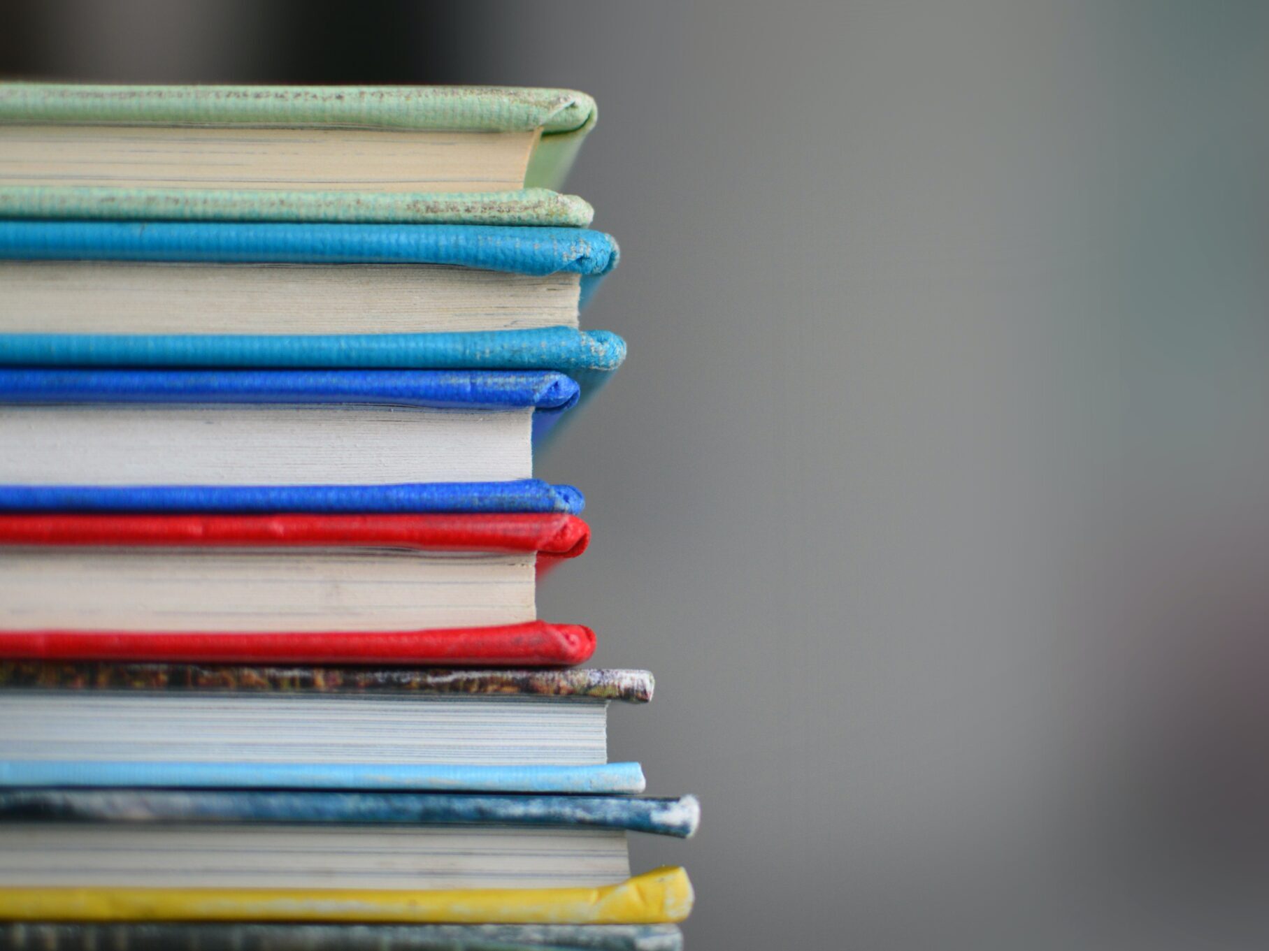 stack of brightly colored books against gray wall