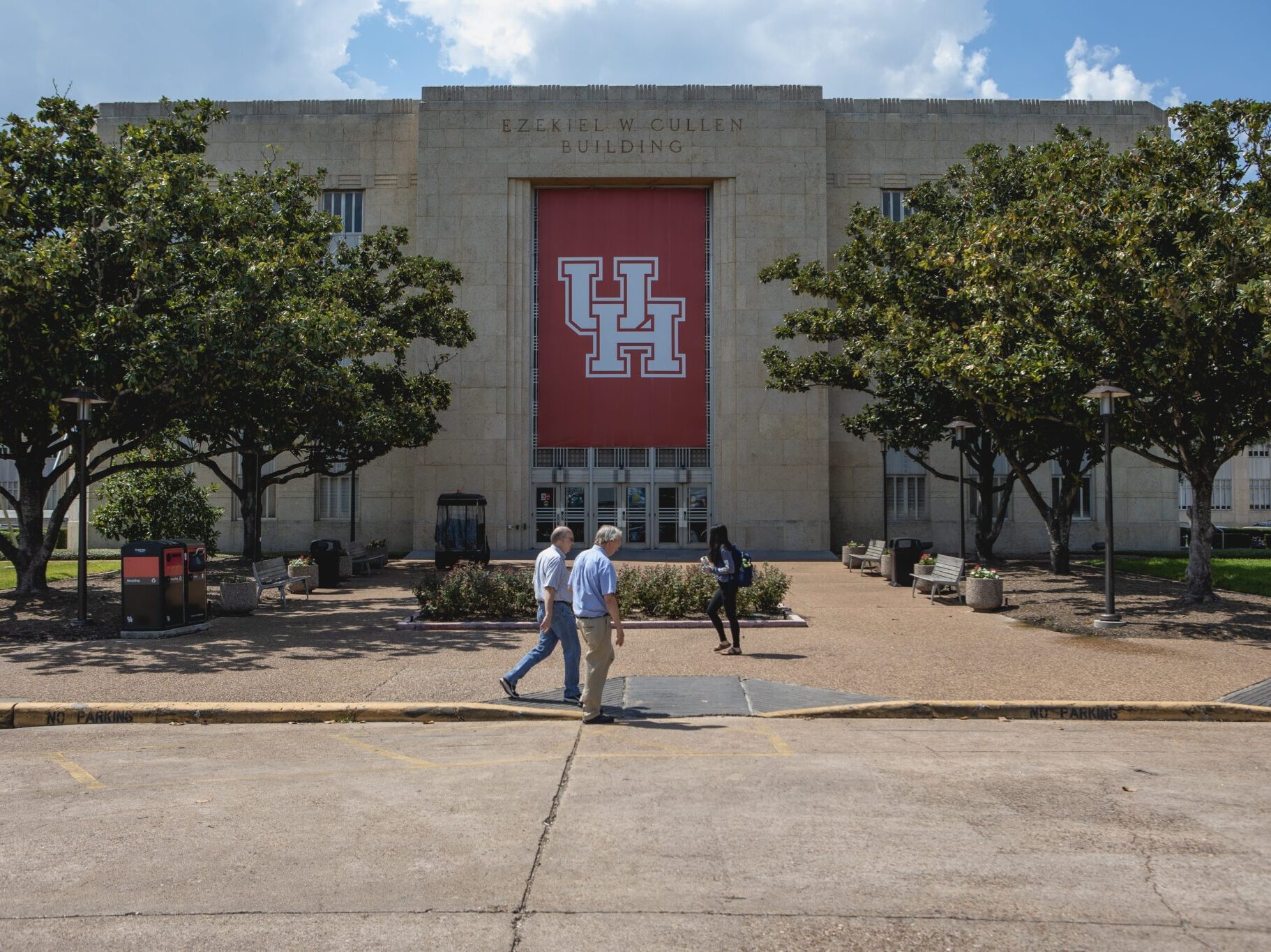 Two students walking by a University of Houston banner.