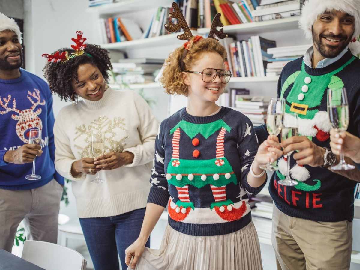 4 people at a party in Christmas sweaters for article Where To Show Off Your Ugly Sweater in Houston