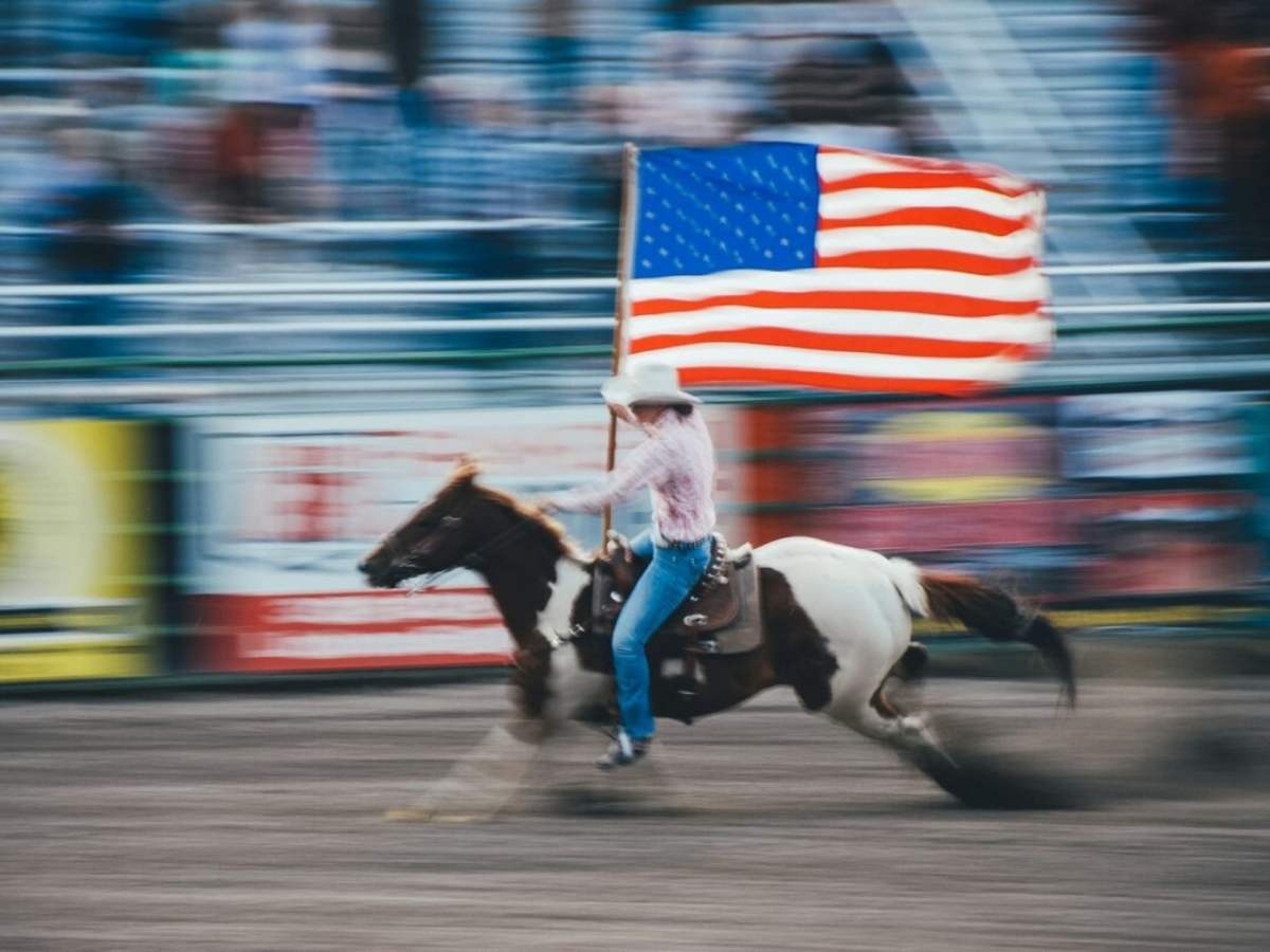 Cowboy riding a horse holding the American Flag for article Houston Livestock Show and Rodeo