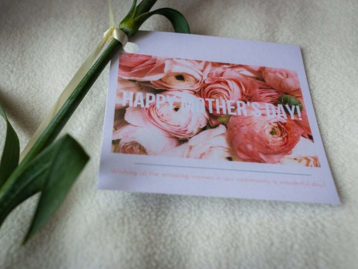 pink and white rose painted on a "Happy Mother's Day" card beside a green stem on a table for article Houston Hospitality: Celebrate Mom in the Bayou City