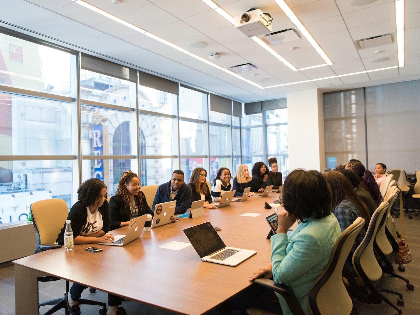 Group of business people sitting together at a conference table chatting for article Administrative Professionals Day: A Year-Round Celebration for newcomers moving to Houston.