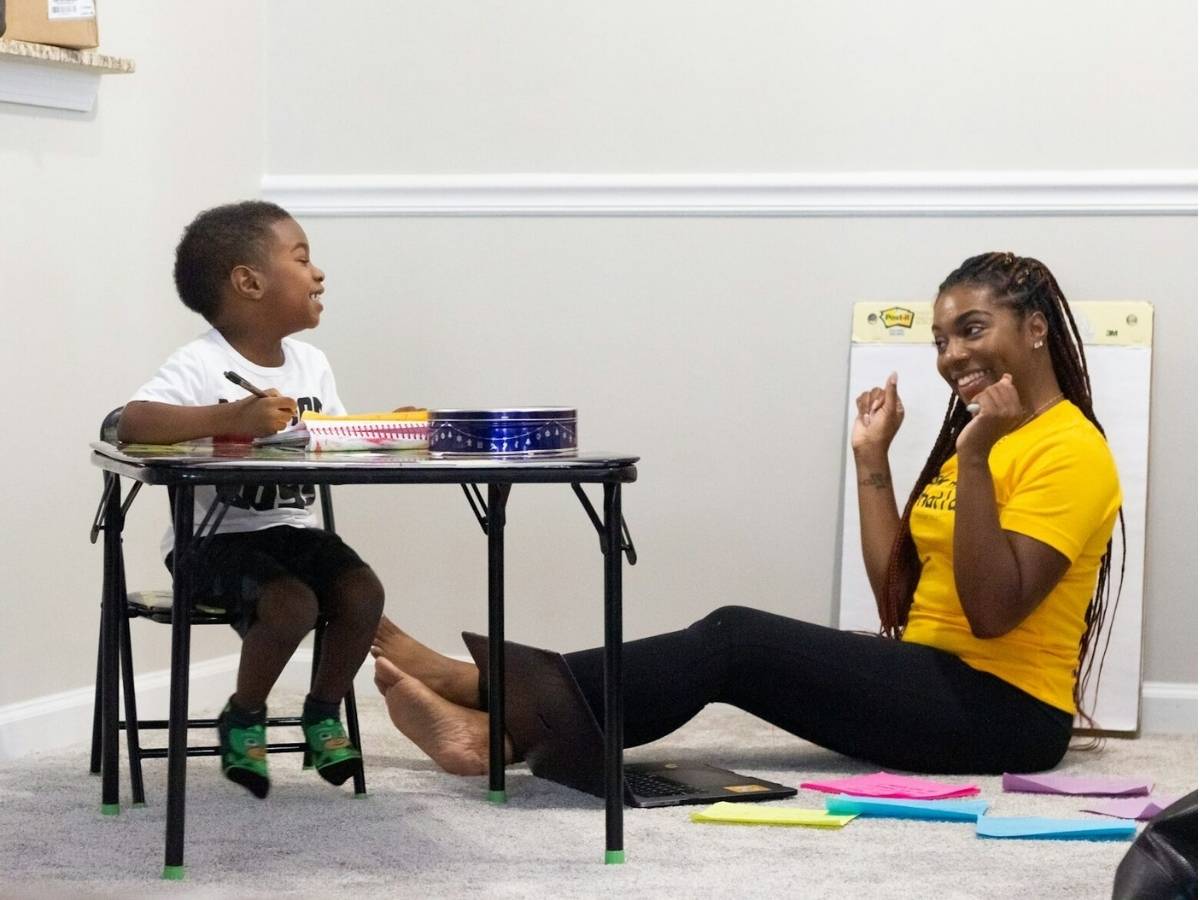 A teacher teaching a student one-on-one with smiles on their faces for article Houston Teacher Appreciation Week for newcomers moving to Houston.