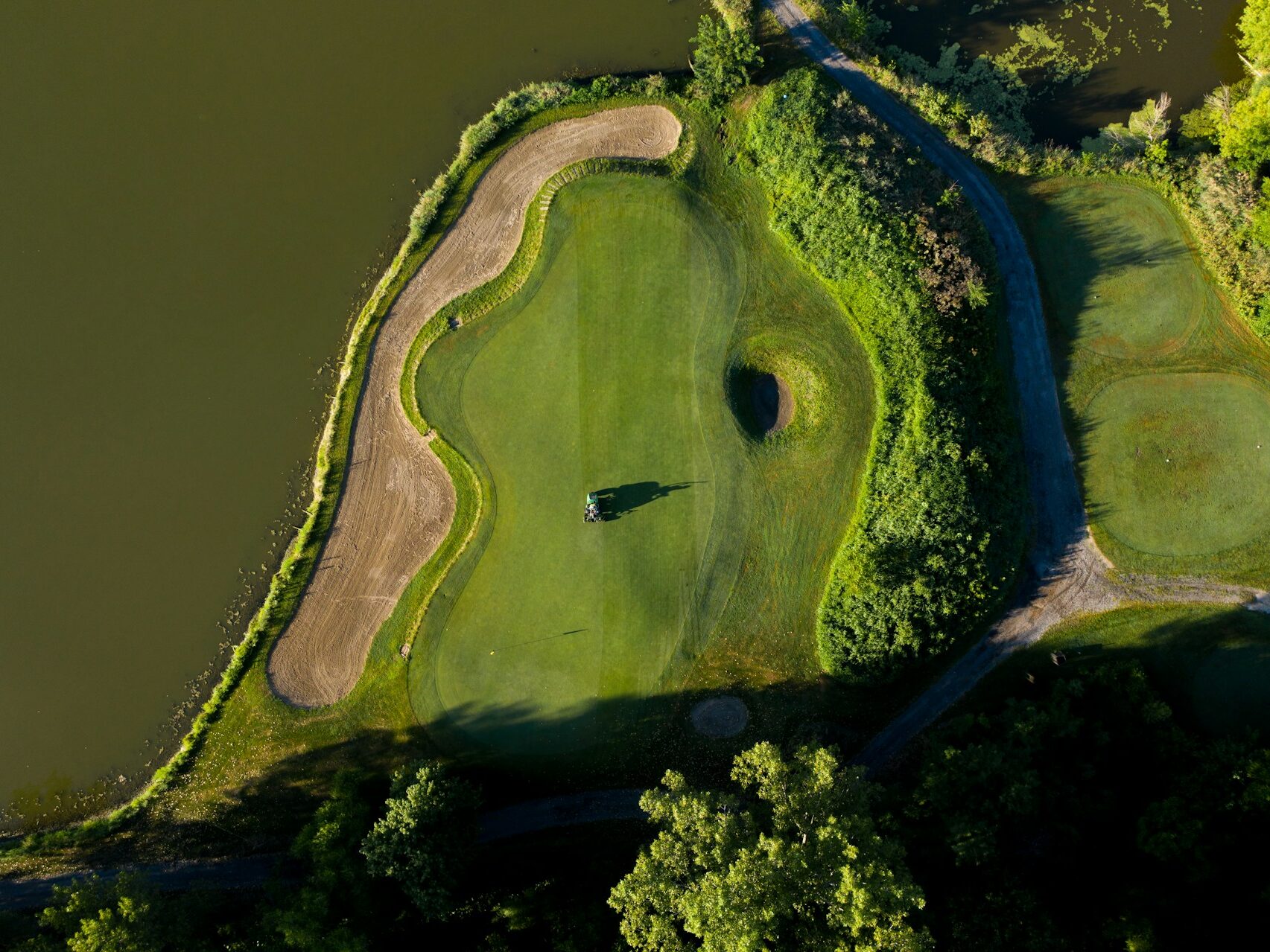 aerial view of a hole at a golf course with water on the left side