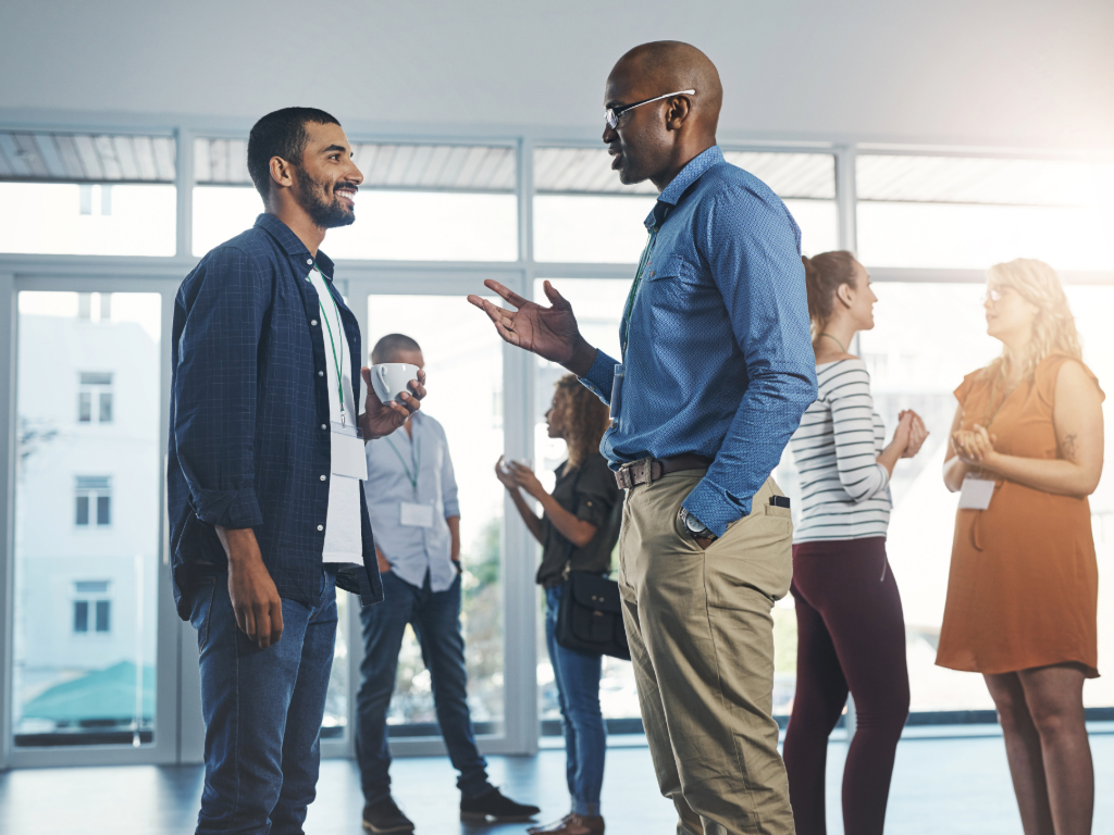 Professionals standing around in groups talking with each other at a networking event.