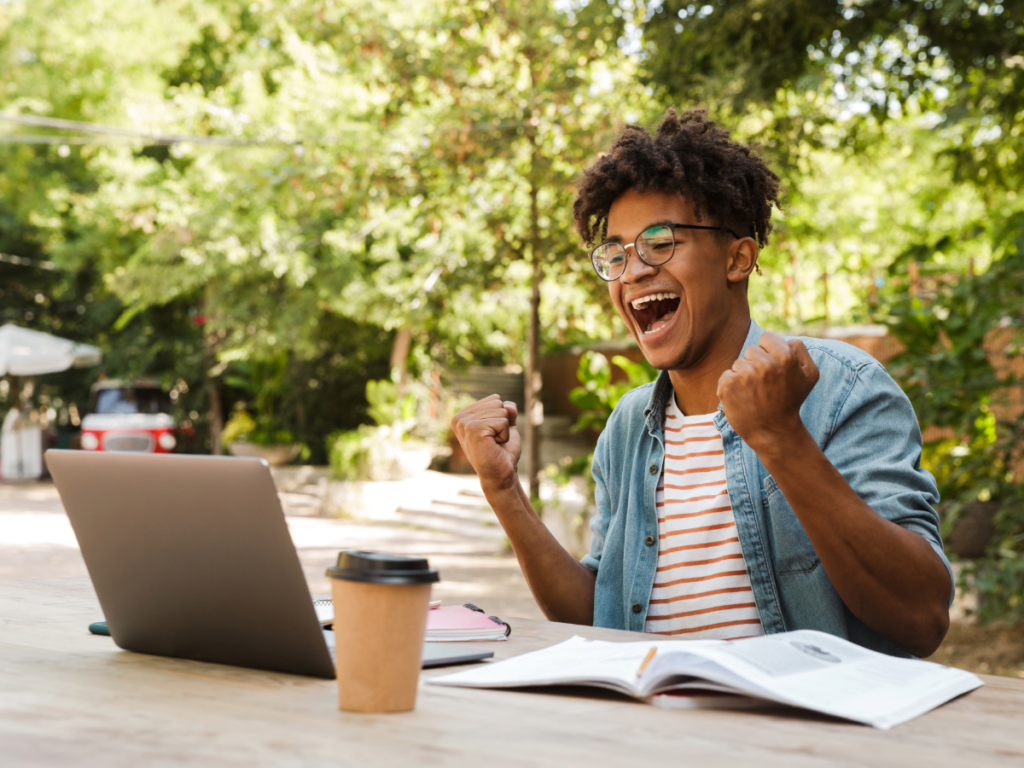 Young boy excited and working on a computer outdoors