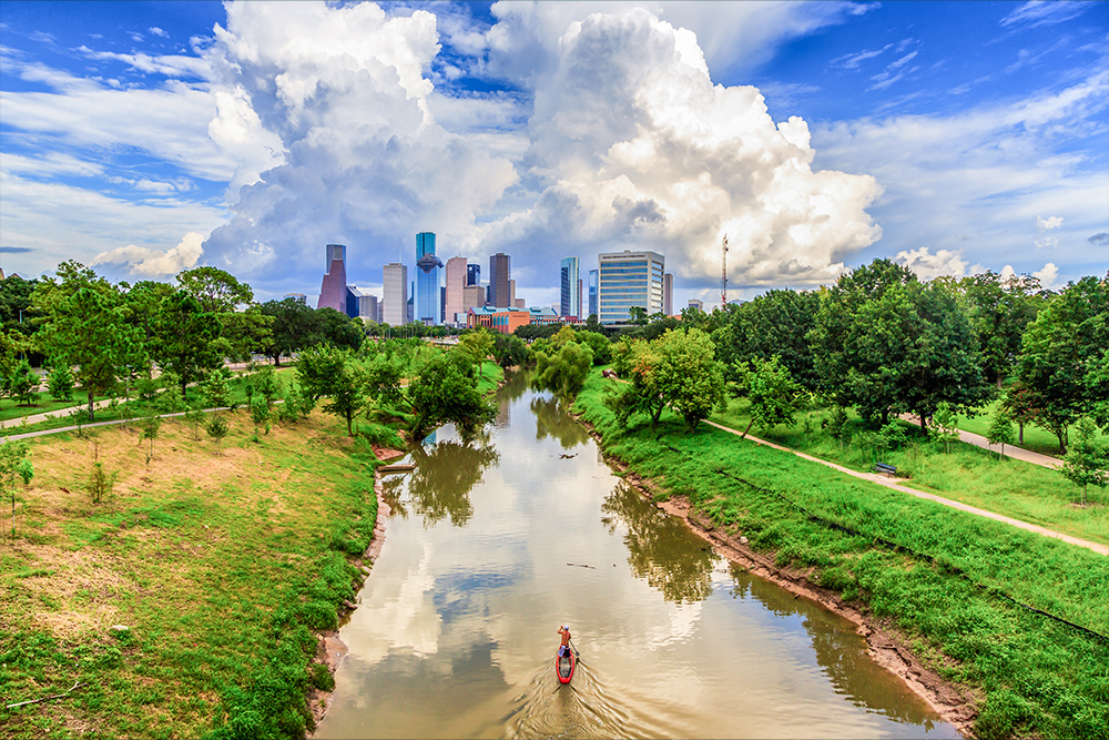 Man paddle boarding with Houston skyline in background