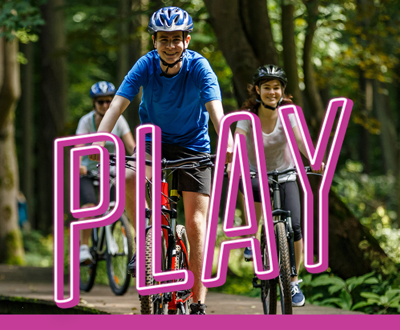 Department Image: PLAY. Father and kids riding bike through trail