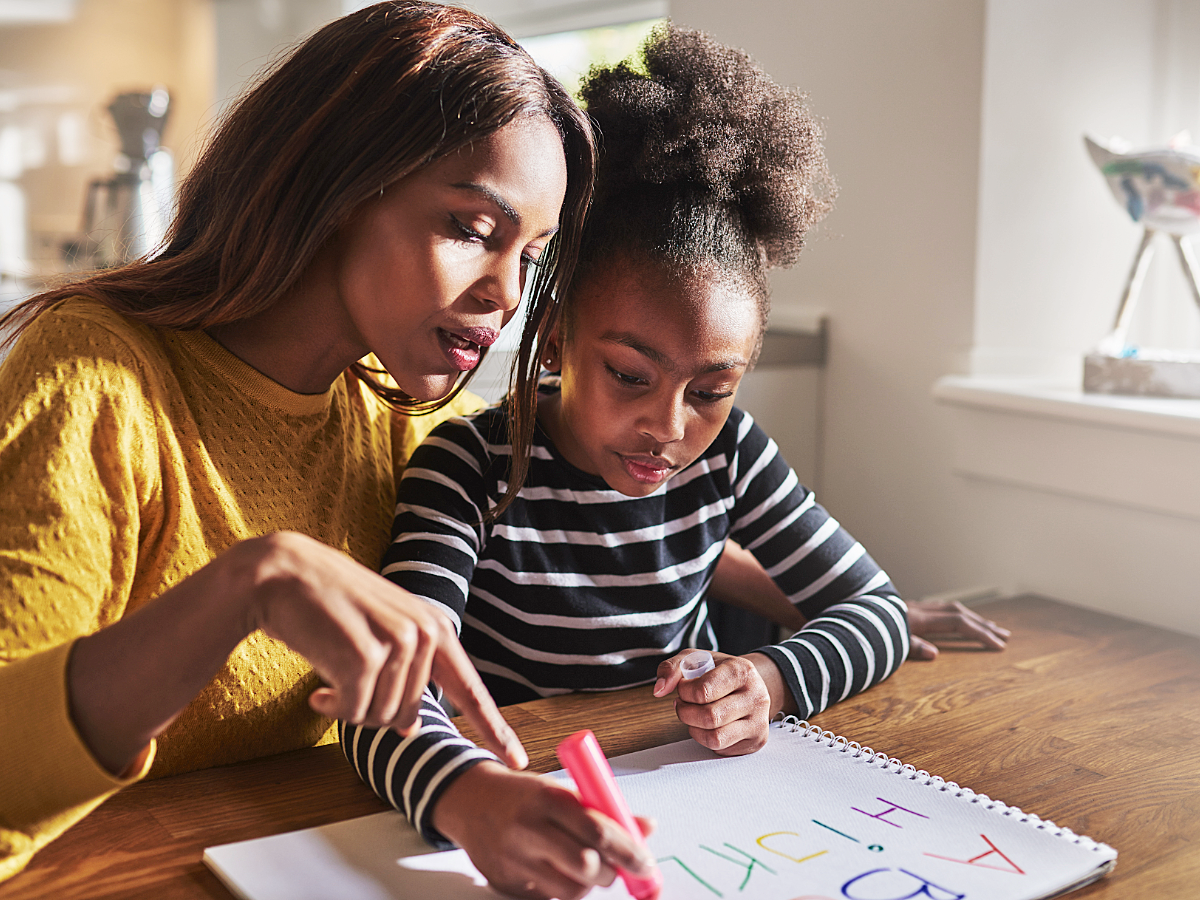 Mother and daughter sitting at a table together. Mother is homeschooling daughter.