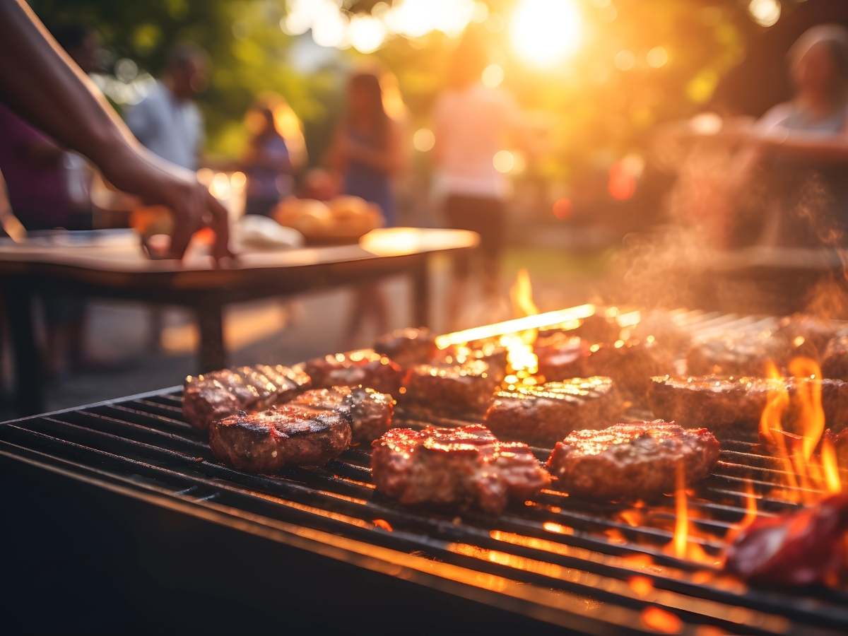 Close up of grill with food and fire and people in the background for article Things to Do Around July 4th in Houston