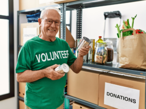 Senior man in green shirt that says volunteer working with donated items.