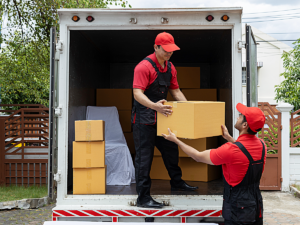 Professional movers moving boxes out of moving truck.