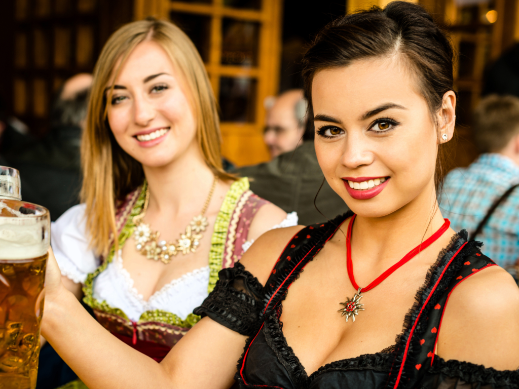 2 Ladies dressed in costume at fall festival with large beer mugs.