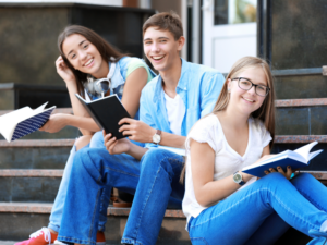 3 kids sitting on front steps of high school with books studying for article - 10 Best College Prep High Schools in Houston for newcomers.