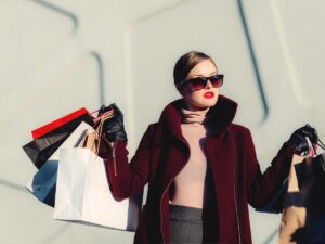 Woman in nice fashionable clothes, hair pulled back, sunglasses on holding lots of shopping bags in both hands for article The Best Shopping in Houston: 12 Shopping Destinations for newcomers moving to Houston.