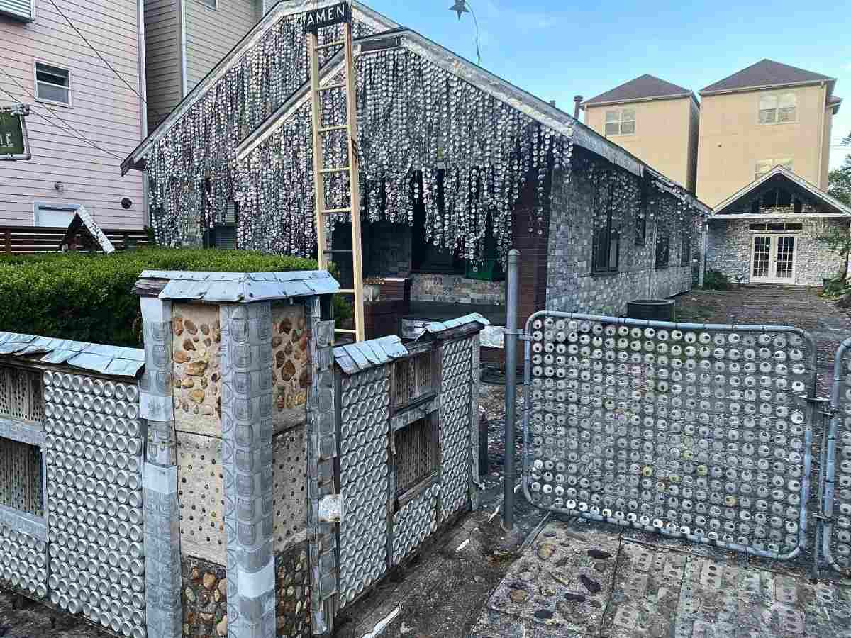 Image of the Beer Can House - front gate made of beer can tops and house made of other beer can parts behind the front gate made of beer cans for article 10 Weird Things to Do in Houston for newcomers moving to Houston.