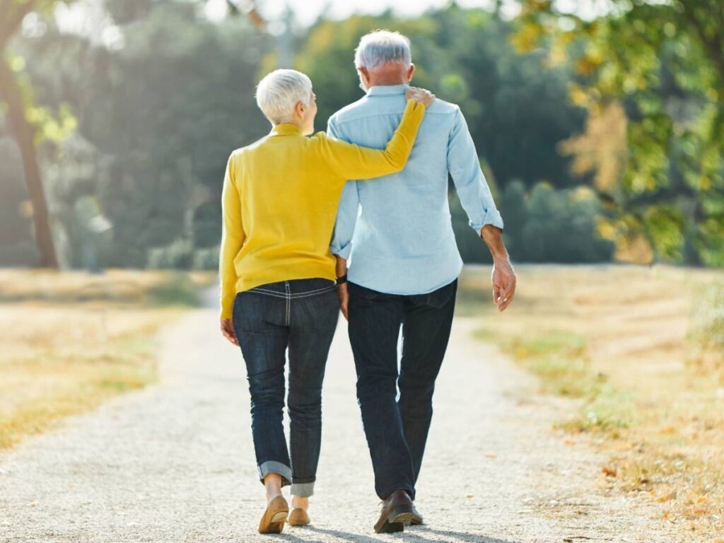 Senior couple walking away from camera on walking path for article Walkable Retirement Communities in Houston for newcomers retiring in Houston.