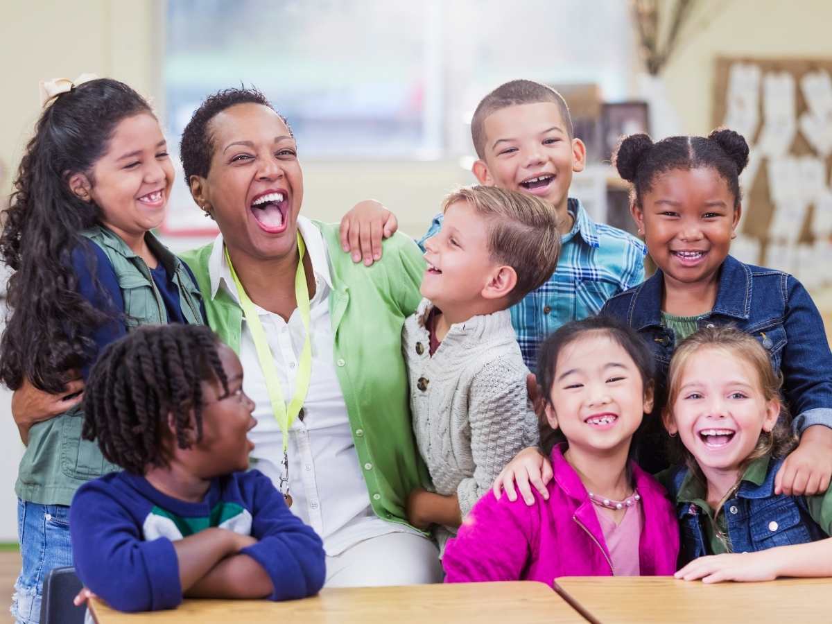 Diverse group of students gathered together with teacher all smiling and laughing for article Understanding Houston ISD vs. Surrounding School Districts for newcomers moving to Houston.